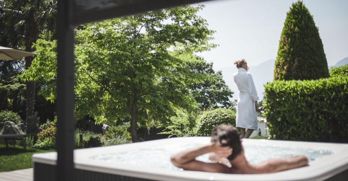 Paar beim Relaxen im Hotwhirlpool auf der Gartenterrasse des 4 Sterne S Hotel Sonnbichl mit Blick auf Meran