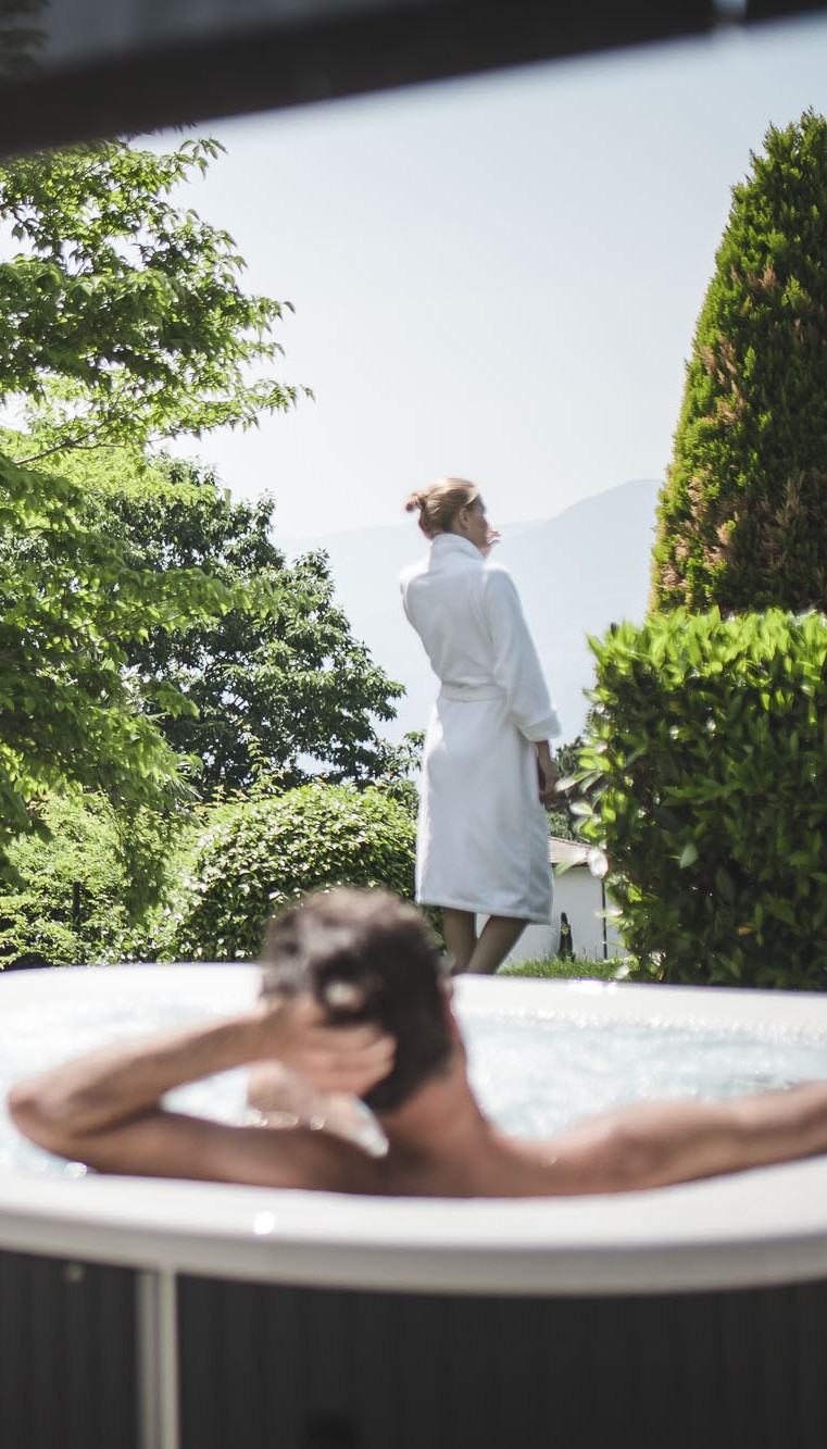 Paar beim Relaxen im Hotwhirlpool auf der Gartenterrasse des 4 Sterne S Hotel Sonnbichl mit Blick auf Meran